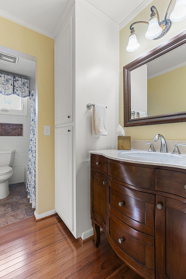 bathroom with toilet, ornamental molding, wood-type flooring, and vanity