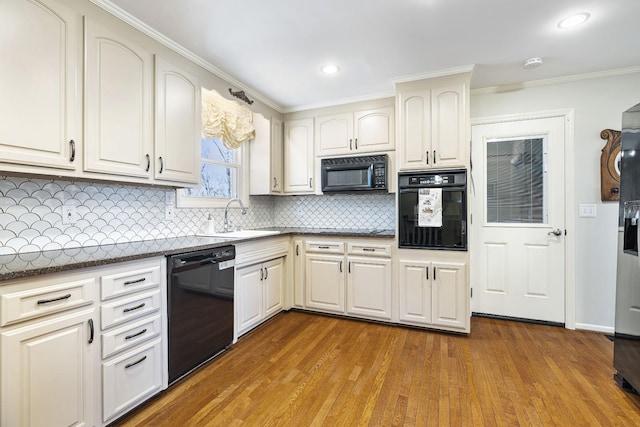 kitchen with black appliances, tasteful backsplash, crown molding, light hardwood / wood-style flooring, and sink