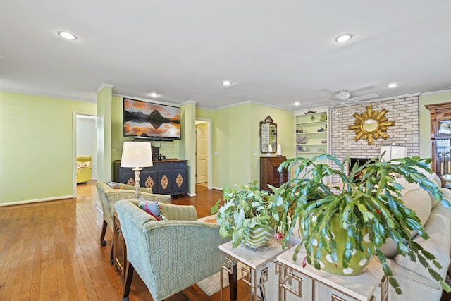 living room featuring ceiling fan, ornamental molding, a fireplace, and hardwood / wood-style flooring