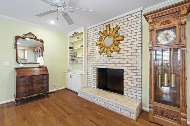 unfurnished living room featuring hardwood / wood-style floors, built in shelves, a fireplace, ornamental molding, and ceiling fan