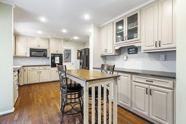 kitchen with dark hardwood / wood-style floors, crown molding, tasteful backsplash, and black appliances