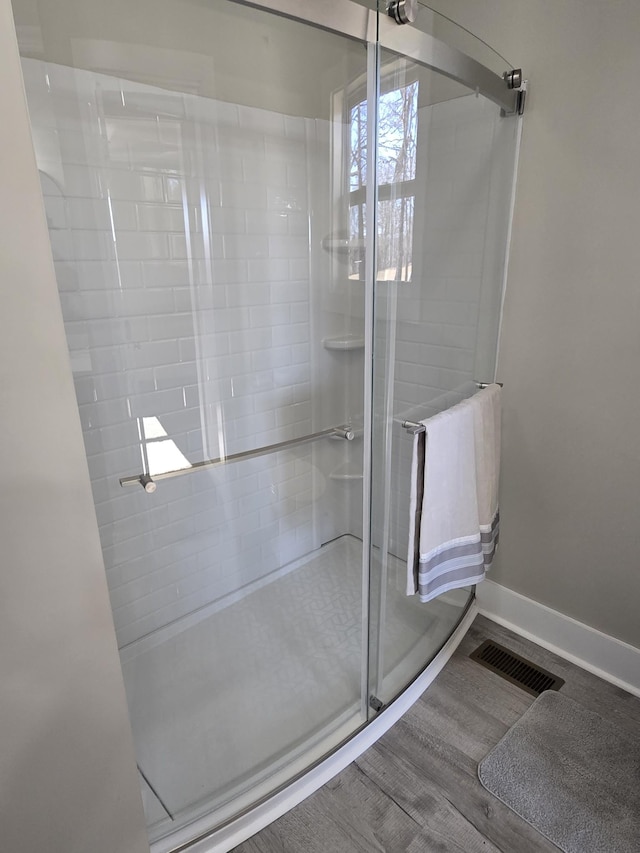 bathroom with a shower with shower door and hardwood / wood-style flooring