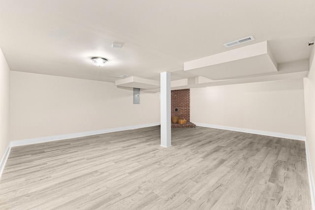 finished below grade area featuring light wood-style flooring, visible vents, and baseboards