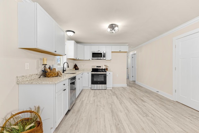 kitchen with crown molding, stainless steel appliances, light wood-style floors, white cabinetry, and a sink