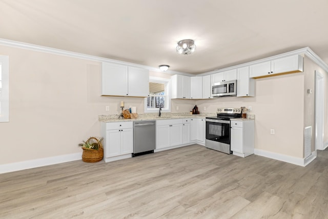 kitchen with appliances with stainless steel finishes, light wood-style flooring, and white cabinets