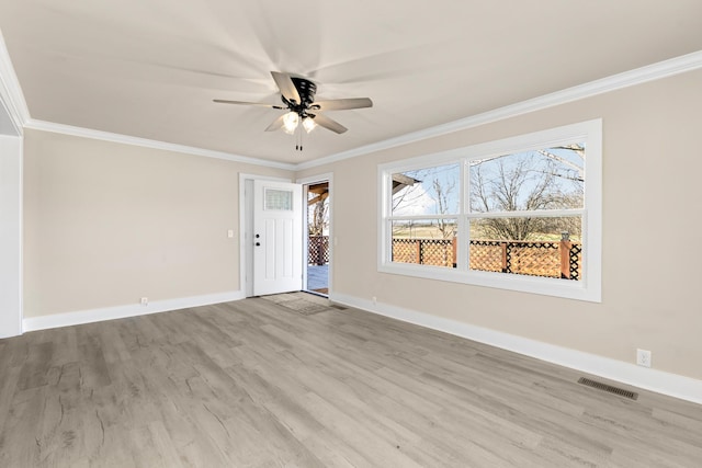 empty room featuring baseboards, visible vents, ceiling fan, ornamental molding, and light wood-type flooring