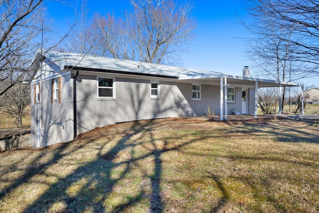 rear view of property featuring metal roof, covered porch, brick siding, a lawn, and a chimney