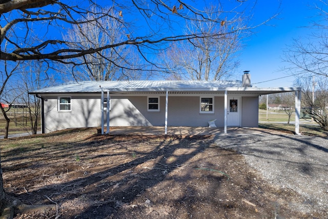 view of front of property featuring a chimney, metal roof, and brick siding