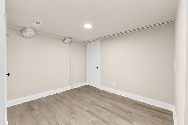 spare room featuring light wood finished floors, visible vents, and baseboards