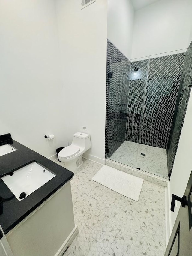 bathroom featuring toilet, vanity, and a tile shower