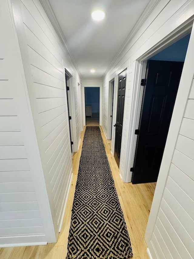 hallway featuring crown molding and light hardwood / wood-style flooring