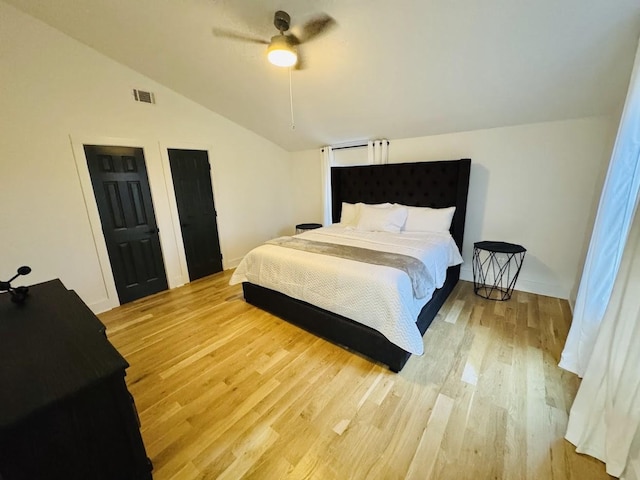 bedroom with ceiling fan, light hardwood / wood-style floors, and vaulted ceiling