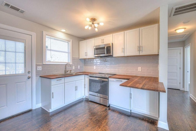 kitchen with appliances with stainless steel finishes, white cabinets, wooden counters, and sink