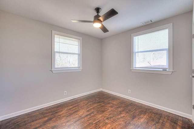 empty room featuring ceiling fan, a healthy amount of sunlight, and dark hardwood / wood-style flooring