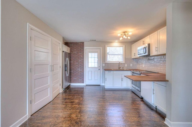 kitchen with decorative backsplash, sink, stainless steel appliances, white cabinets, and butcher block counters