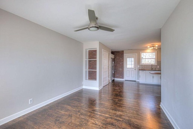 unfurnished living room with ceiling fan, dark wood-type flooring, and sink