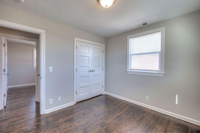 unfurnished bedroom featuring dark hardwood / wood-style floors and a closet