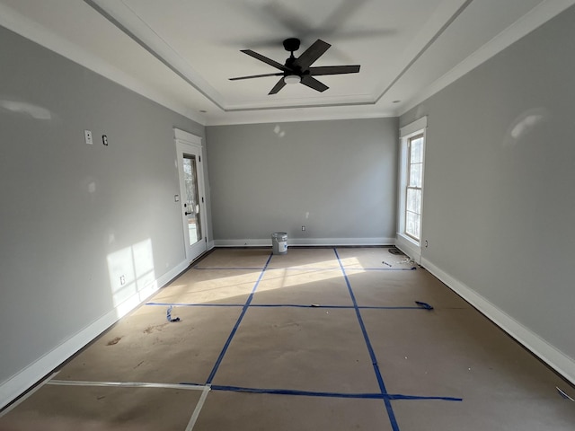 empty room featuring ceiling fan, a raised ceiling, and baseboards