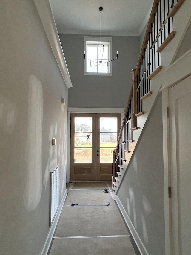 entryway featuring visible vents, a towering ceiling, stairway, ornamental molding, and french doors