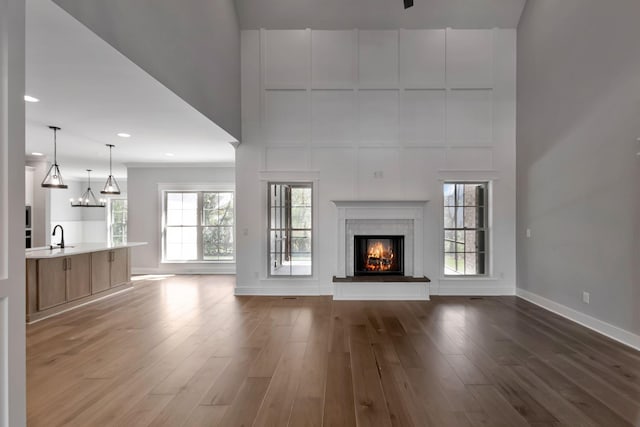 3025 Shady Forest Dr, Murfreesboro, TN 37128 - unfurnished living room with baseboards, wood finished floors, a glass covered fireplace, and a sink