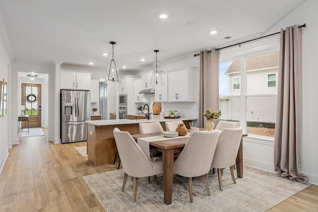 dining room featuring sink, crown molding, and light hardwood / wood-style flooring