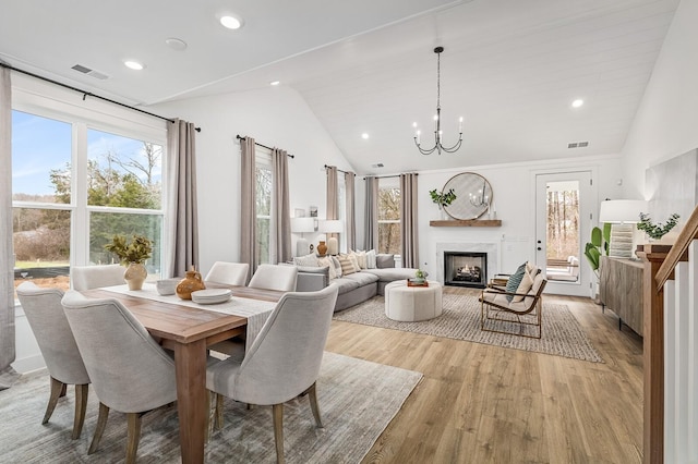 dining area featuring lofted ceiling, a chandelier, and light hardwood / wood-style flooring