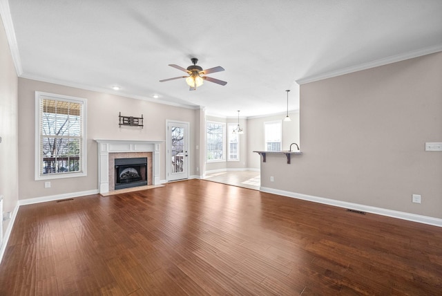 unfurnished living room featuring hardwood / wood-style flooring, ornamental molding, a tile fireplace, and ceiling fan