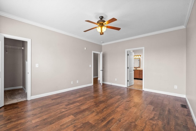 unfurnished bedroom with crown molding, ceiling fan, ensuite bathroom, a spacious closet, and a closet