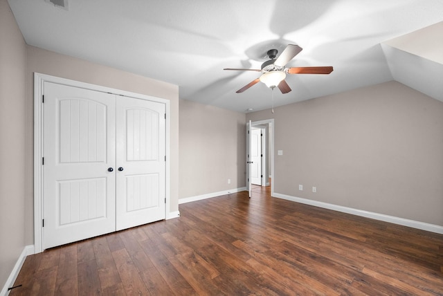 unfurnished bedroom with dark hardwood / wood-style flooring, lofted ceiling, ceiling fan, and a closet