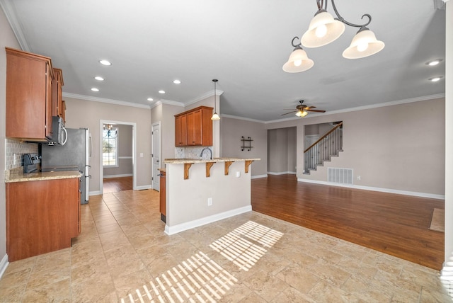 kitchen with tasteful backsplash, decorative light fixtures, a breakfast bar area, and crown molding