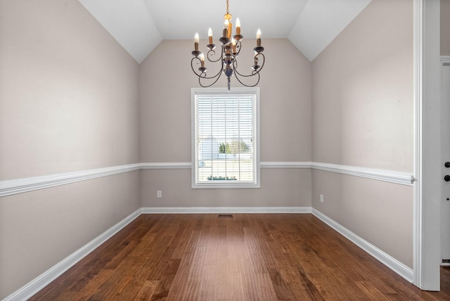 empty room featuring lofted ceiling, dark hardwood / wood-style flooring, and a chandelier