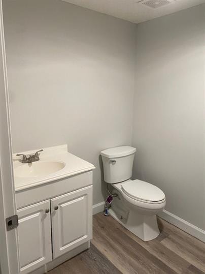 bathroom with toilet, vanity, and hardwood / wood-style floors