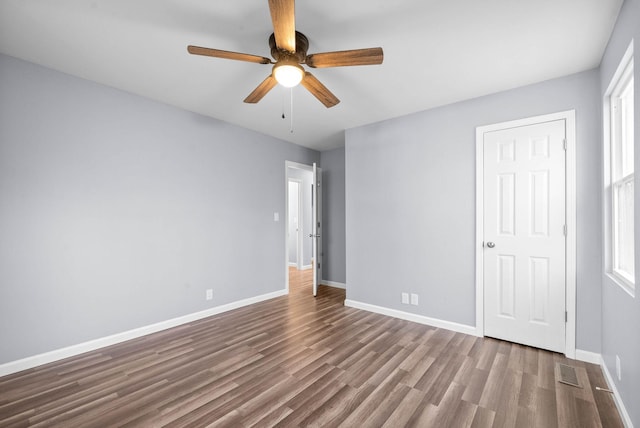 unfurnished bedroom with ceiling fan, multiple windows, and hardwood / wood-style flooring