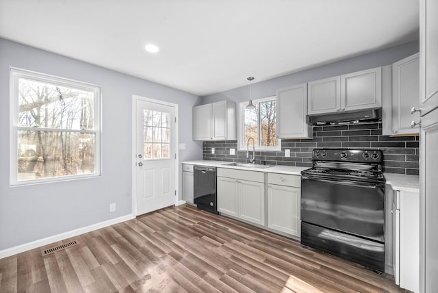 kitchen featuring black appliances, a healthy amount of sunlight, sink, and hanging light fixtures