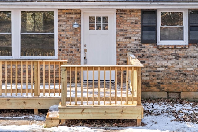 snow covered property entrance featuring a deck