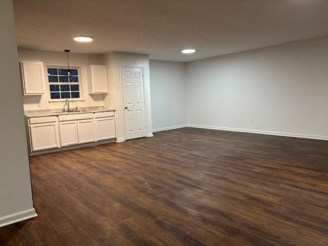 kitchen featuring decorative light fixtures, white cabinets, dark wood-type flooring, and sink