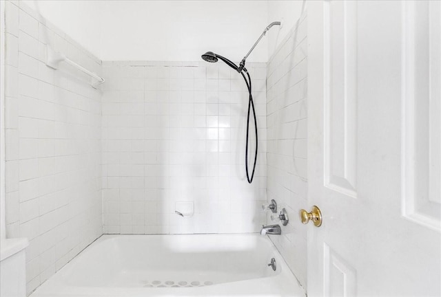 bathroom with toilet and tiled shower / bath combo