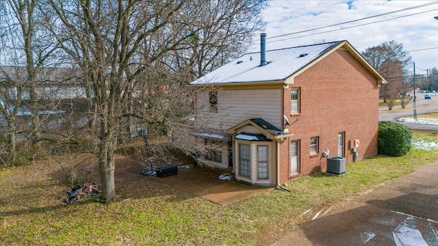 rear view of house with cooling unit and a lawn