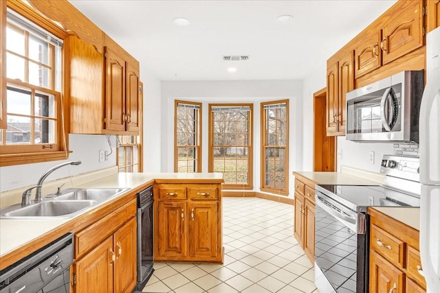 kitchen with light tile patterned floors, sink, appliances with stainless steel finishes, and kitchen peninsula