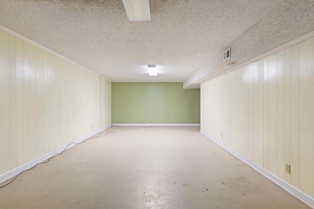 basement with wood walls and a textured ceiling