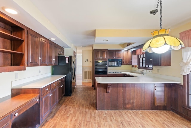 kitchen featuring black appliances, light hardwood / wood-style floors, sink, kitchen peninsula, and a breakfast bar