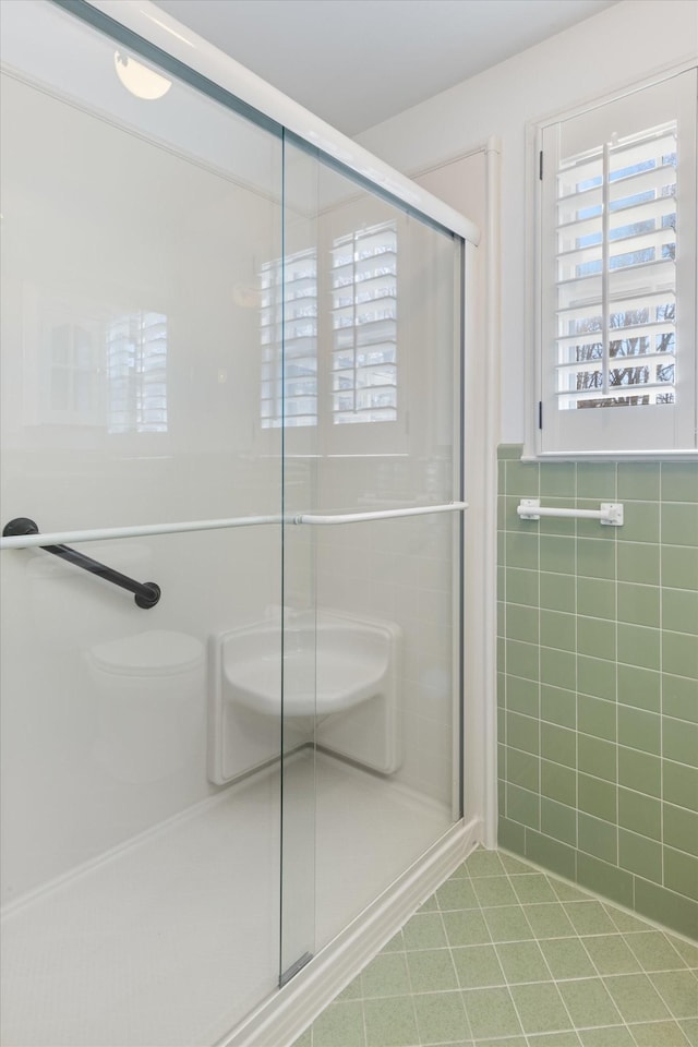 bathroom with tile walls, an enclosed shower, and tile patterned flooring