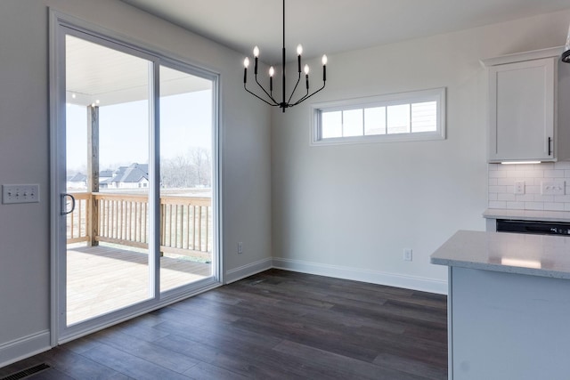 unfurnished dining area with dark wood-type flooring and a notable chandelier