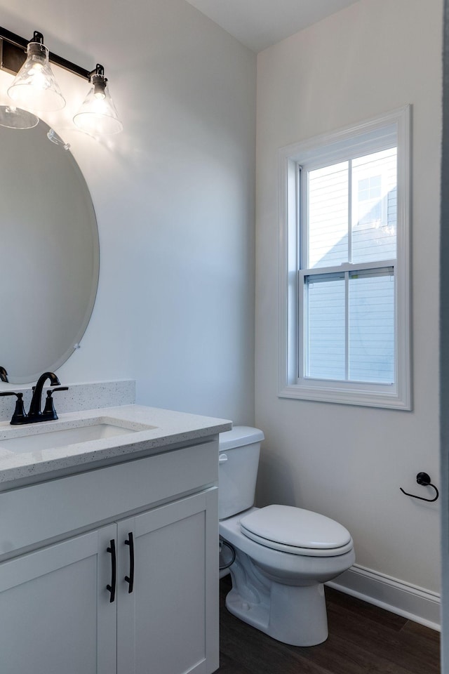 bathroom with toilet, vanity, and wood-type flooring