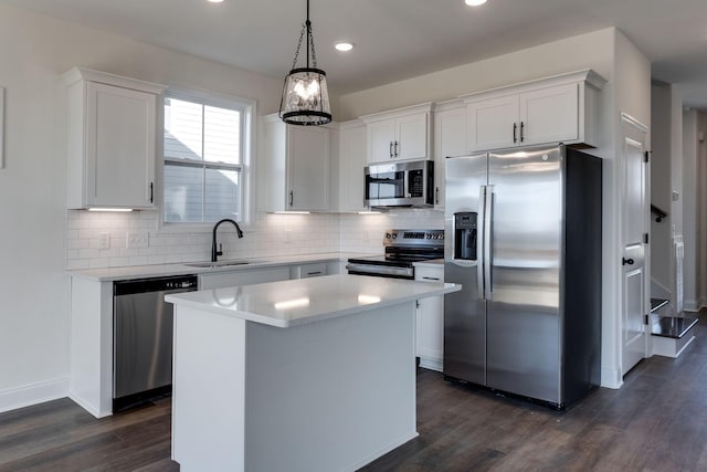 kitchen with stainless steel appliances, white cabinetry, a kitchen island, and sink