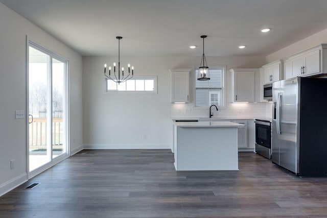 kitchen featuring hanging light fixtures, stainless steel appliances, and white cabinetry