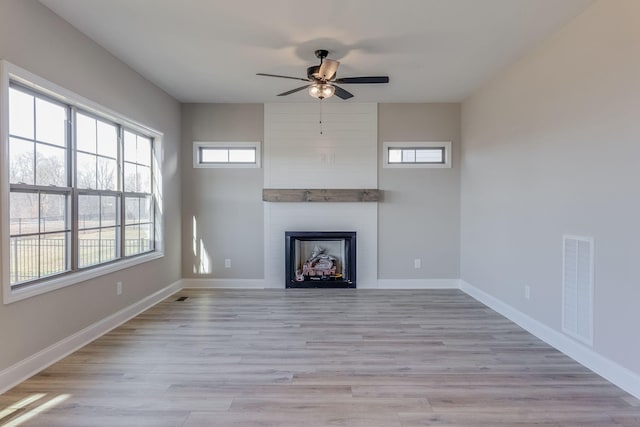 unfurnished living room featuring ceiling fan, light hardwood / wood-style floors, and a fireplace