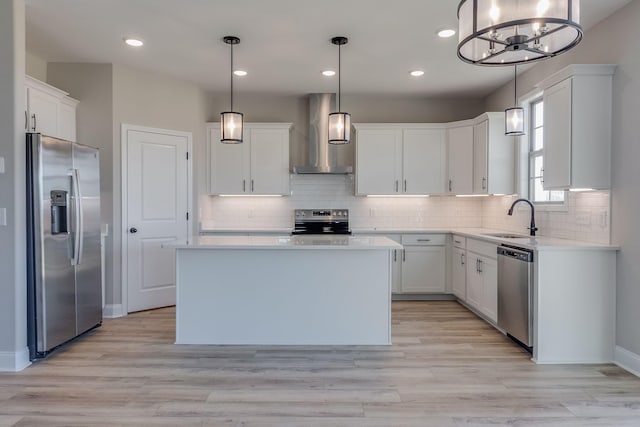 kitchen with sink, appliances with stainless steel finishes, pendant lighting, and wall chimney range hood