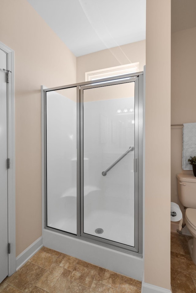 bathroom featuring a shower with shower door and toilet