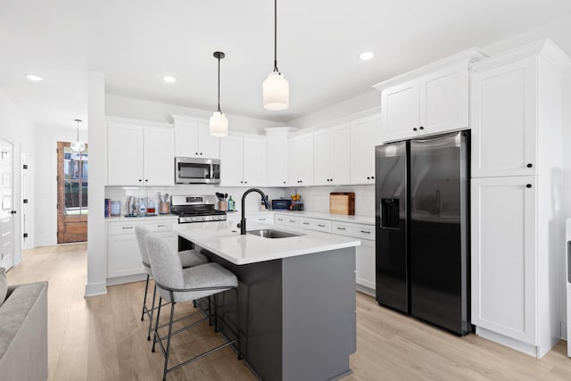 kitchen with white cabinetry, appliances with stainless steel finishes, tasteful backsplash, decorative light fixtures, and sink